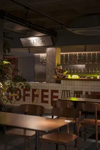 Inviting coffee shop interior with a bar, chairs, tables, potted plants, and international signs