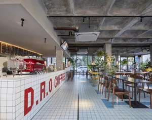 A modern coffee shop with a large open area, seating options, potted plants, artwork, and good lighting
