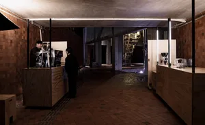 Indoor space with a brick floor, people, bottles, and a cup, creating a casual and social atmosphere