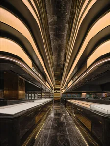A modern lobby with marble flooring, gold accents, and high ceilings, featuring multiple chairs and an open space