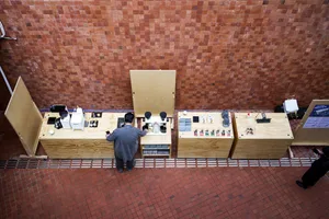 A casual indoor space with a brick wall, a wooden countertop, and various objects and people arranged in a relaxed atmosphere