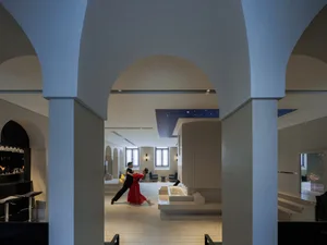 A lively indoor lobby with a dance performance, surrounded by chairs and benches, with a comfortable atmosphere