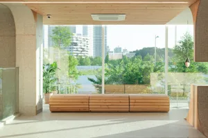 A well-lit indoor space with wooden benches and large windows allowing sunlight to enter