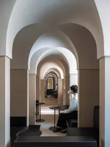 一位顧客坐在餐廳桌邊，周圍有多張椅子與拱形牆面，營造溫暖親切的氛圍