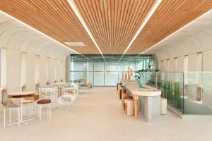 Open restaurant interior with wooden floors and walls, dining tables, chairs, potted plants, and a modern ambiance