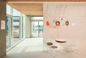 Open living area with three chairs, two dining tables, and a large window allowing natural light to enter the space