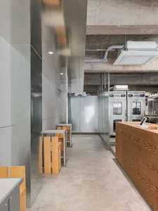 Empty restaurant interior with a cement floor and walls, featuring wooden tables and chairs in a clean and well-organized atmosphere