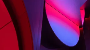 A large building with a purple and pink hue, featuring red and blue elements in its facade, creating a vibrant and eye-catching atmosphere