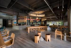 Modern restaurant interior with wooden tables and chairs, creating a warm atmosphere with multiple dining tables and chairs