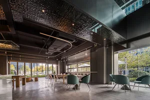 A modern dining space with multiple chairs and tables, concrete walls, and overhead lighting fixtures