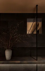 Dark room with black stone walls, a window, and a potted plant, featuring two vases and a somber atmosphere