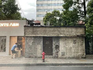Old stone building with a red fire hydrant in front, two people standing outside, daytime lighting