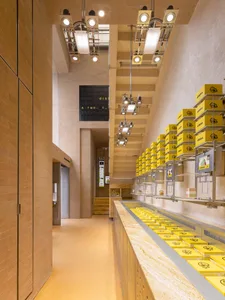 明亮溫馨的麵包店內部，配有大型展示櫃陳列黃色盒子與各式商品