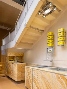 Well-lit modern kitchen with marble countertops, sink, and stairs, in a clean and organized residential environment