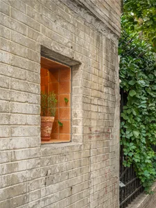Exposed brick wall with a potted tree on a window ledge, adding greenery to the space
