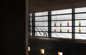 Modern bar area with marble countertop, bottles, and wine glasses, featuring a sophisticated and organized space