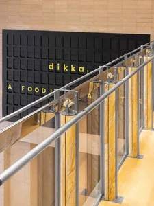 Modern office space with a yellow accent wall, black lettering, and natural light from windows with curtains