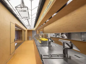 Industrial kitchen with countertops, sinks, and various food preparation items, two people working in the space