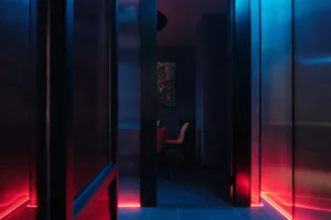 Dimly lit room with black walls, two chairs, and a doorway to another room