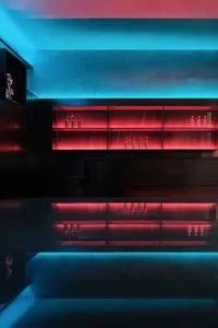 Modern bar area with a black countertop, red glow, and bottles on the counter