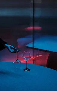 A contemporary dining space with a clear glass table, minimalist decorations, and a unique touch of a remote control in a wine glass
