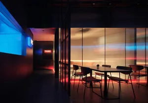 A modern dining space with a large table and multiple chairs, warm atmosphere, and red accents on the walls