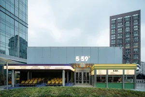 Contemporary urban building with a glass exterior, a large sign reading 569, and a seating area with chairs inside