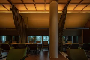 Cozy modern dining space with wooden floors and walls, natural light, and multiple dining tables and chairs