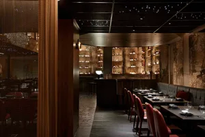 A well-lit restaurant interior with wooden walls and floors, multiple chairs around dining tables, and a comfortable atmosphere for guests