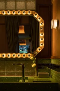 Bathroom with sink area, mirror, and decorative vases, featuring a potted plant and ambient lighting
