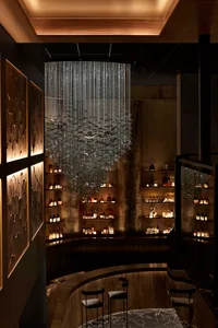 昏暗空間中設有大型水晶燈、烈酒瓶與酒杯的精緻酒吧區