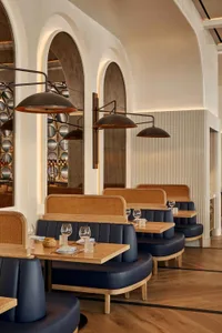 A restaurant interior with wooden tables and chairs, wine glasses, and a warm atmosphere