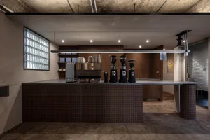 Industrial kitchen with a counter featuring espresso machines, cups, and a clean, organized atmosphere