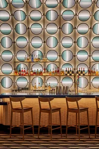 A social bar scene with a long counter, chairs, and bottles of liquor, creating a welcoming atmosphere for patrons