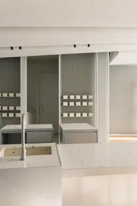 Modern bathroom with white tiles on the walls and countertops, two sinks, and marble countertops, well-lit and inviting