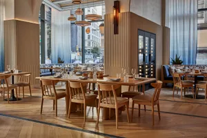 Sophisticated restaurant interior with a large dining table, chairs, potted plants, and fine china and glassware