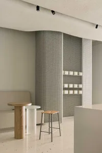 A modern office space with a white countertop, wooden table, two chairs, and a large mirror on a wall, giving a clean and well-organized atmosphere