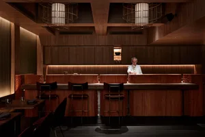 Inviting restaurant interior with wooden walls and floors, featuring dining tables and chairs, and decorative bowls on the tables