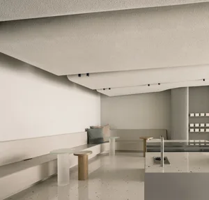 Modern kitchen and dining area with white walls, two benches, a sink, and a refrigerator, giving off a minimalist vibe