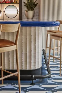 A modern bar area with a marble countertop, wooden chairs, and a stylish atmosphere