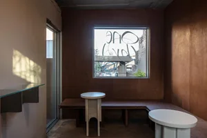 木質牆面與地板的餐廳，設有餐桌、長椅與單椅，背景窗戶灑入自然光線