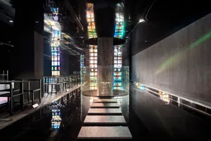 A modern interior space with a glass staircase surrounded by colorful glass panels and metal stairs