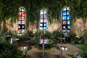 Indoor space with stained glass windows, three round tables, and four chairs, suitable for events or social gatherings