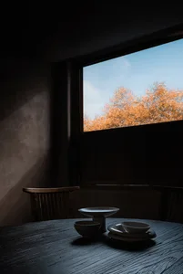 A well-lit dining area with a wooden table and chairs, set for a meal with two bowls and a cozy atmosphere