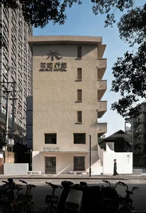 A modern Asian building with a white concrete facade, featuring a large lobby area with people walking and interacting