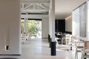 A modern restaurant with a clean and inviting dining area featuring multiple tables and chairs, with wine glasses on some tables, set for service