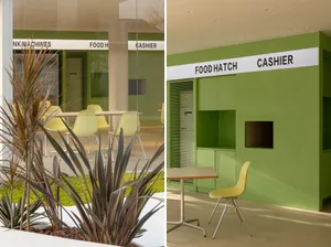 Cozy restaurant with chairs and tables, industrial setting with green wall and TV, modern and functional design