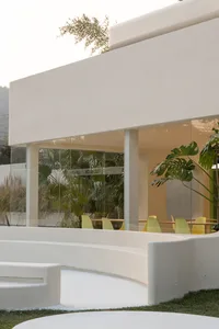 Inviting indoor space with a large white wall, glass doors, yellow chairs, and potted plants
