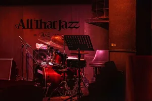 A darkened room with a jazz band performing on stage, featuring a chair and various musical instruments