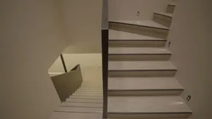 A photo of a staircase with a black railing in an indoor setting